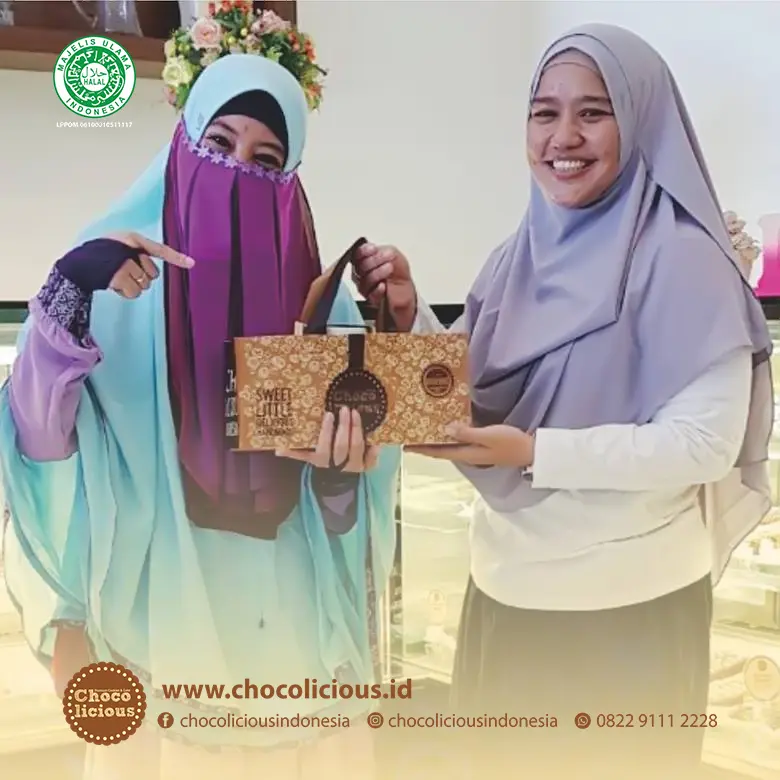 Peggy berpose di depan Toko Cake Chocolicious di Makassar, menunjukkan kegembiraannya dengan kue cokelat di tangannya.